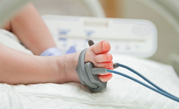 Close-up of a baby's arm with a blood pressure cuff during a hospital checkup.