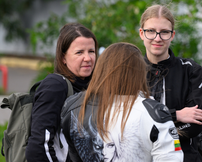 Smiltė su akiniais, jos mama kairėje ir motociklininkų kolonos vedlė Anastasija renginyje „Purpurinis važiavimas už neišnešiotukus“.